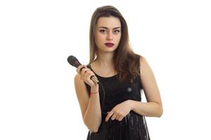 morena de vestido preto canta com microfone foto