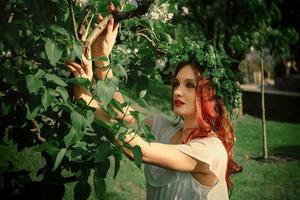 jovem atraente com cabelo ruivo e coroa de flores na cabeça foto