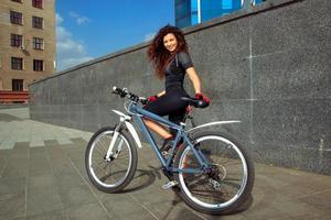 mulher feliz com cabelo ruivo encaracolado em bicicleta foto
