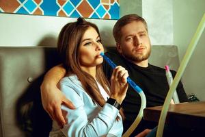 casal relaxando com cachimbo de água no café foto