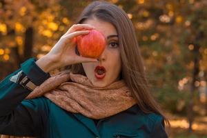 jovem fica no parque e mantém a maçã perto dos olhos foto