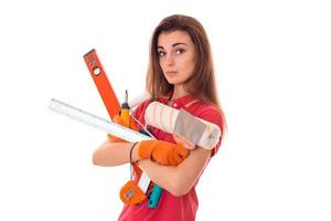 jovem construtora encantadora de uniforme com muitas ferramentas faz renovação isolada em fundo branco foto