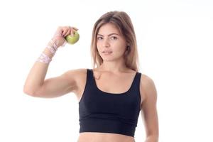 garota fica diretamente e mostra uma maçã em uma mão, seus músculos foto