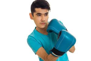 retrato de jovem forte na camisa azul praticando boxe em luvas isoladas no fundo branco foto