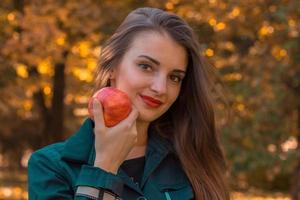 linda garota mantém a maçã grande na mão parece reto e sorridente close-up foto