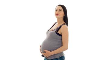 linda mulher grávida morena tocando sua barriga e olhando para cima isolado no fundo branco foto