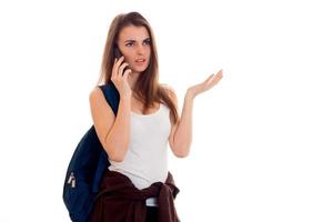 uma jovem de camiseta e mochila no ombro com uma pessoa séria falando ao telefone foto