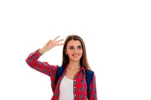 jovem sorridente em uma camisa vermelha e um portfólio nos ombros olha para o lado e mostra o gesto com a mão foto