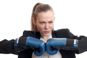 jovem loira bonita com uma cara séria mantém as mãos em luvas de boxe isoladas no fundo branco foto