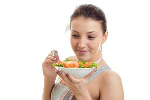 linda jovem fica perto do prato com salada de legumes e um close-up de um sorridente foto