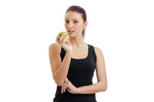 linda garota sem maquiagem segura na mão uma maçã verde e olha de perto foto