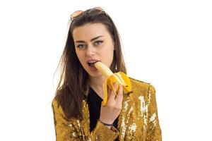 retrato de uma jovem que fica no incrível estúdio e segura banana perto da boca foto
