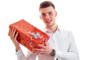 cara jovem maravilhoso na camisa sorrindo e segurando um close-up de presente foto