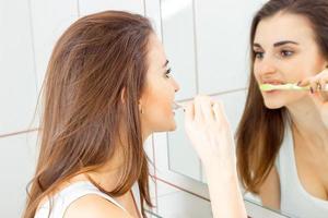 mulher escovando os dentes na frente do espelho foto