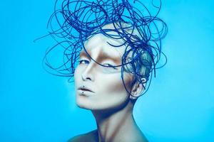 mulher atraente com arte corporal criativa e penteado em fundo azul foto