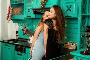 retrato de duas irmãs em lindos vestidos se divertindo na cozinha de casa e sorrindo para a câmera foto