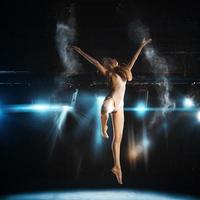 salto de bailarina no palco do teatro contra holofotes foto