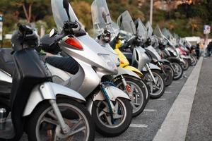 muitas scooters e motocicletas estão estacionadas em uma longa fila. foto