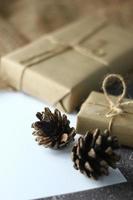 presentes de férias. caixa de presente de natal e ano novo embrulhada em pinhas de papel pardo e papel branco e canetas colocadas sobre a mesa, copie o espaço. foto