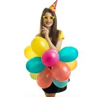 retrato vertical de uma linda jovem que fica na frente da câmera e segura óculos escuros e muitos balões grandes
