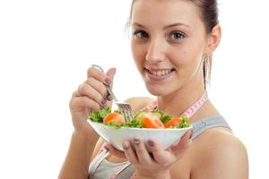 linda jovem come uma salada e sorri na câmera foto