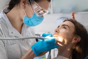 dentista trata os dentes de uma menina em uma clínica foto