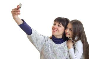 mãe com filha faz selfie em estúdio e sorri foto