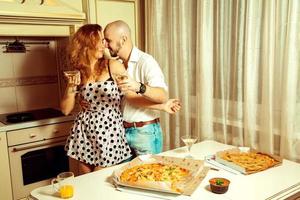 casal jovem bonito flertando em uma festa com álcool e pizza foto