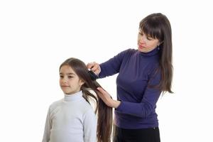 mãe penteando o cabelo de sua filhinha fofa foto