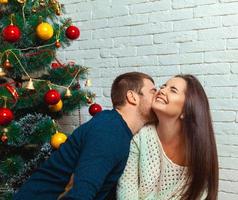 cara beija uma garota debaixo da árvore no natal foto