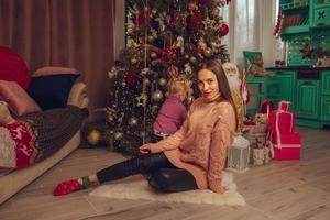 encantadora mãe e filha na árvore de natal foto