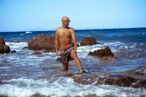 homem bonito na costa rochosa marinha foto