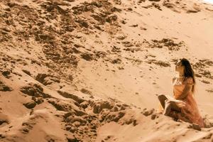 linda jovem senta-se em um deserto foto