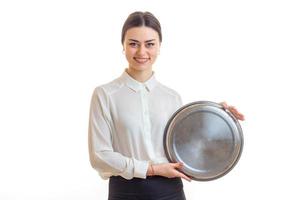 atraente jovem garçonete segurando uma grande bandeja redonda para utensílios de cozinha foto