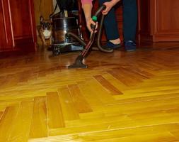 um aspirador de pó em um parquet de madeira coleta a água derramada. bocal e um close-up do aspirador de pó. limpeza molhada de parquet com um aspirador de pó moderno. foto