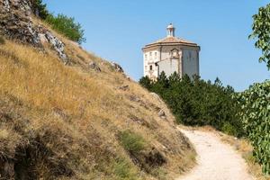 calascio, itália-9 de agosto de 2021-igreja de santa maria della pieta no caminho que leva a rocca calascio durante um dia ensolarado foto