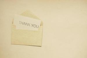 mensagem de agradecimento e envelope na mesa de madeira foto