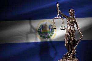 bandeira de el salvador com estátua da senhora justiça e balança judicial em quarto escuro. conceito de julgamento e punição foto