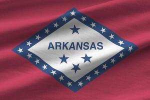 arkansas nos bandeira do estado com grandes dobras acenando perto sob a luz do estúdio dentro de casa. os símbolos e cores oficiais no banner foto