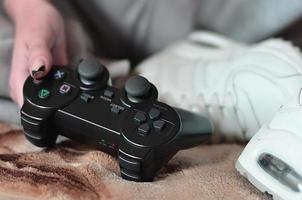 controlador de jogo preto moderno nas mãos de uma jovem sentada foto