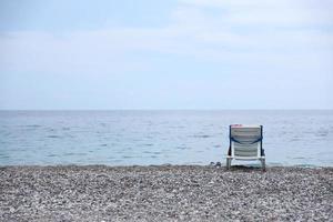 cadeira no banco de seixos com o mar e a praia foto