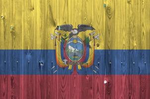 bandeira do equador retratada em cores brilhantes de tinta na parede de madeira velha. banner texturizado em fundo áspero foto