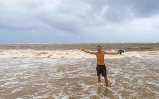 homem está na praia durante o furacão e gosta do méxico. foto