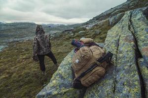 feche a mochila turística no penhasco na foto do conceito do vale da montanha