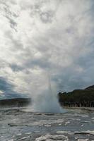 os turistas apreciam a foto da paisagem da erupção do gêiser