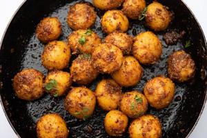 Batatas Bombay assadas caseiras. Batatinhas fritas ou aloo com sementes de jeera e coentro em tigela foto