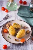 batatas hasselback assadas com alho e alecrim em um prato. almoço caseiro. visão vertical foto