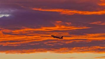 avião na frente de nuvens vermelhas brilhantes no vermelho da noite foto