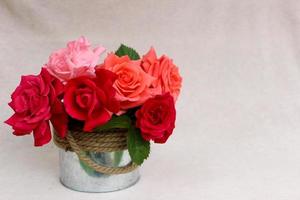 lindo buquê de rosas coloridas em caixa de metal arredondada isolada em fundo rosa com copyspace grátis para texto, imagem para cartão de boas-vindas, papel de parede, calendário, cartaz, cartão postal floral de primavera foto