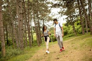 casal jovem sorridente andando com mochilas na floresta foto